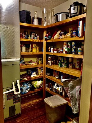 A compact storage area with shelves stocked with canned goods, bags, and containers.