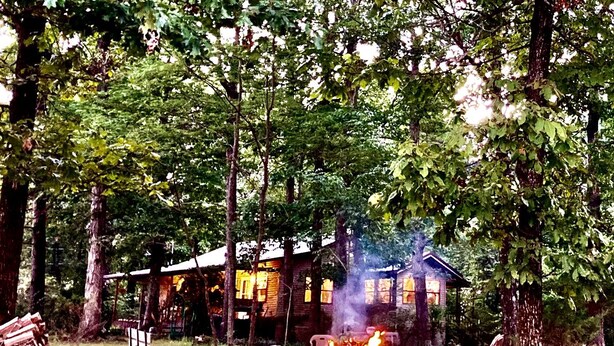 Eine rustikale Holzhütte mit Kamin, umgeben von Bäumen.
