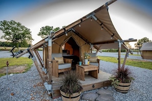 Une tente dotée d’une terrasse en bois, d’un canapé, d’une petite table et de plantes en pot.