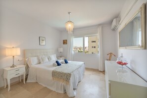 Una habitación de hotel con cama, mesitas de noche, lámpara, espejo y vistas a la ciudad.