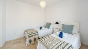 Ein Hotelzimmer mit zwei Betten, einer Kristallleuchter und einem Nachttisch mit Lampe.