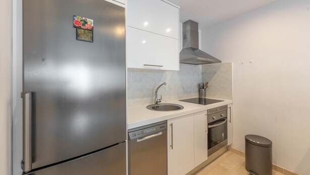 Eine kleine Küche mit einem Edelstahlkühlschrank, einem eingebauten Backofen und einem Geschirrspüler.