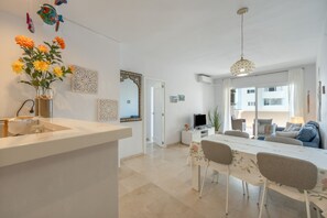 A modern kitchen with a white countertop and a dining area with a table and chairs. - Apartment 'Balcon Del Puerto' with Sea View, Wi-Fi and Air Conditioning (Estepona)