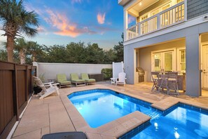 A backyard with a swimming pool, lounge chairs, a barbecue area, and a two-story building with a balcony. - Nolan's Nook|Private Pool|Elevator|Golf Cart (Inlet Beach)
