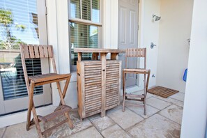 A wooden bench and two chairs outside a building with a tiled floor and a door. - Nolan's Nook|Private Pool|Elevator|Golf Cart (Inlet Beach)