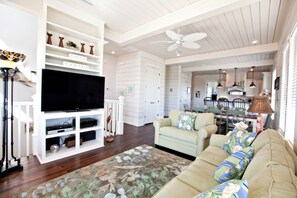 A living room with a TV, white cabinets, a sofa, and a ceiling fan. - Nolan's Nook|Private Pool|Elevator|Golf Cart (Inlet Beach)