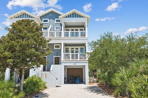 A two-story beachfront house with a covered porch, a garage, and a driveway leading to the entrance. - Nolan's Nook|Private Pool|Elevator|Golf Cart (Inlet Beach)