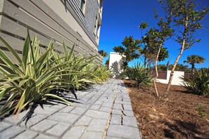 A paved pathway leading to a building with a grey exterior and a clear blue sky above. - Nolan's Nook|Private Pool|Elevator|Golf Cart (Inlet Beach)