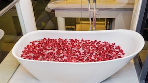 Une baignoire blanche, isolée, remplie de pétales de roses rouges.
