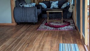 Une pièce chaleureuse avec un plancher en bois, un ensemble de canapés, une petite table et un tapis à motifs.