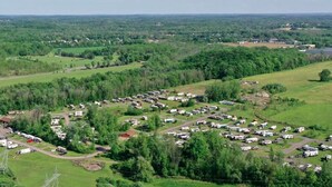A campground with RVs and trailers, a river, and surrounding greenery.