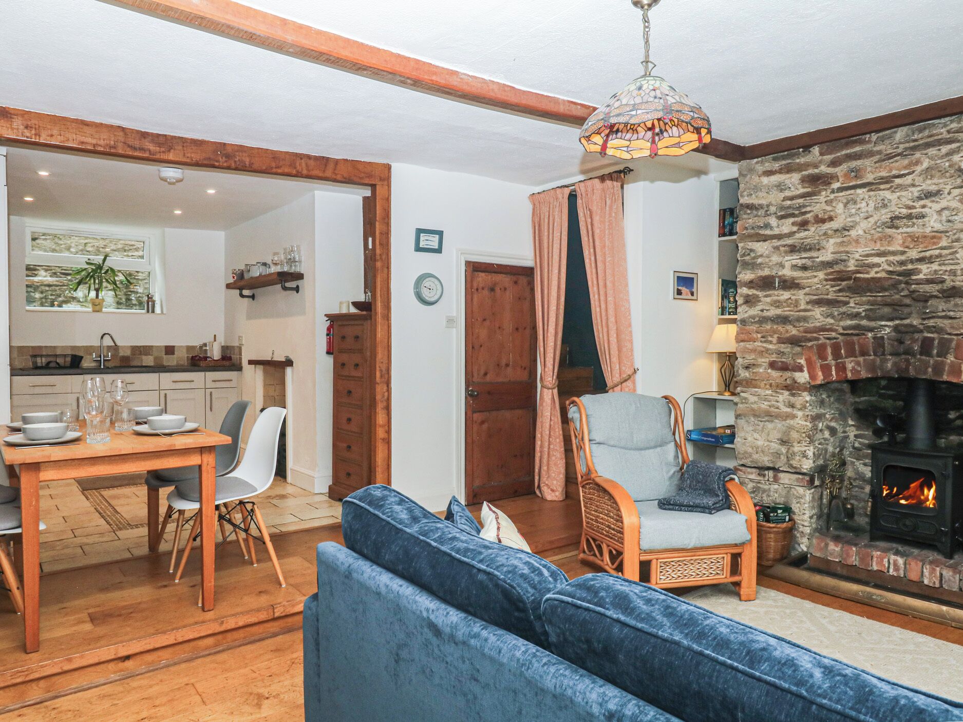 A cozy living room with a fireplace, a dining area, and a kitchen visible through an open door.