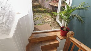 Una escalera de madera que lleva a un balcón con una planta en maceta.