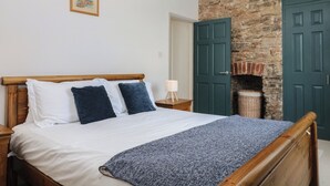 Un dormitorio con una cama de madera, una pared de piedra y una puerta verde.