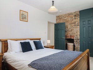 Ein Schlafzimmer mit einem hölzernen Bett, einer Steinwand und einer grünen Tür.