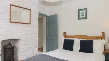 Une chambre à coucher avec un lit, une cheminée, une porte et un tableau encadré au mur.
