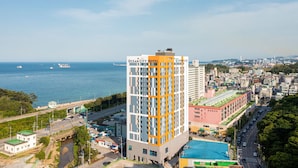 Un hotel con vista al mar, una piscina y un paisaje urbano al fondo.