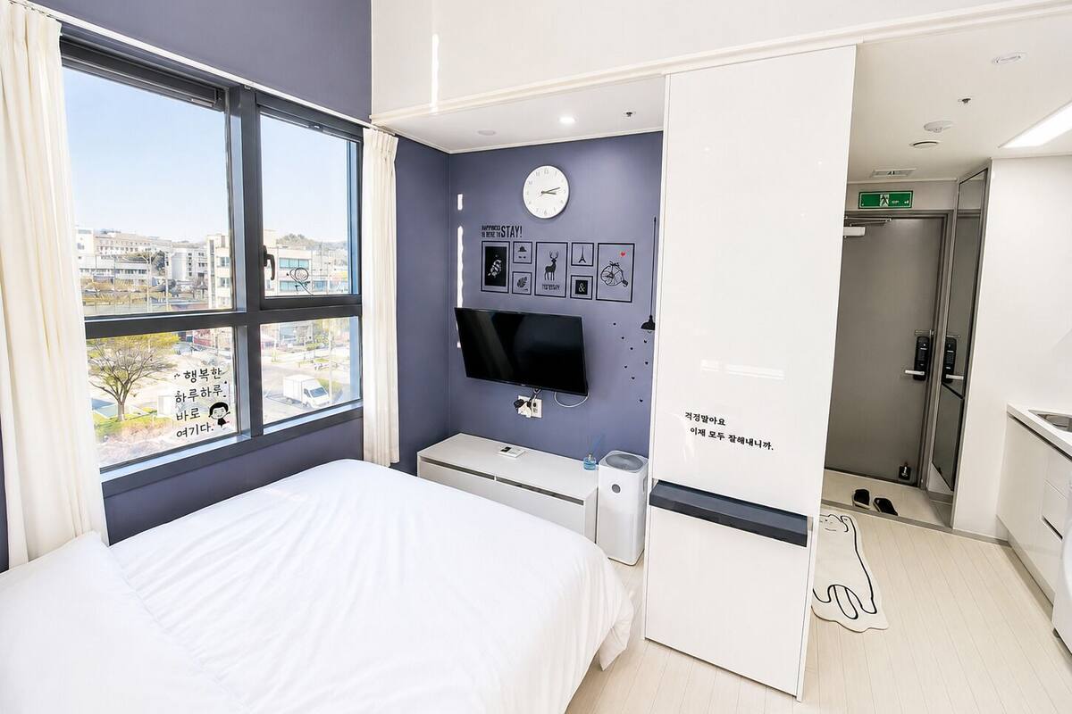 Ein Hotelzimmer mit Bett, Fernseher, Schreibtisch, Fenster mit Blick und Badezimmer.