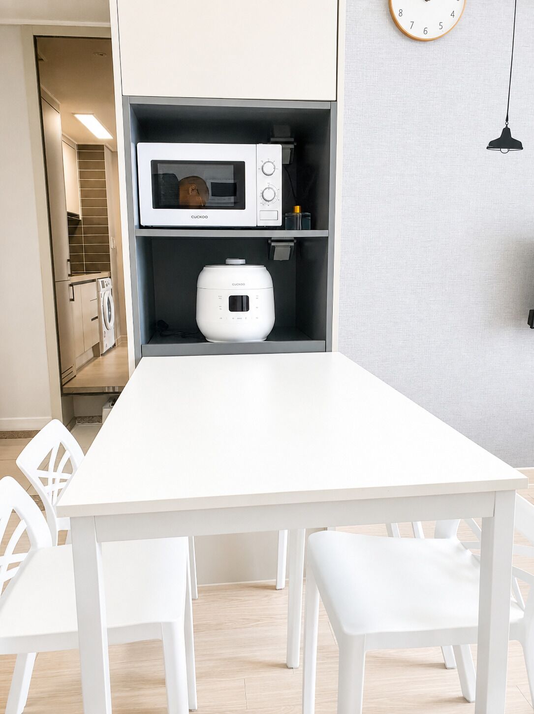 Una cocina moderna con microondas, cocedor de arroz y un reloj en la pared.