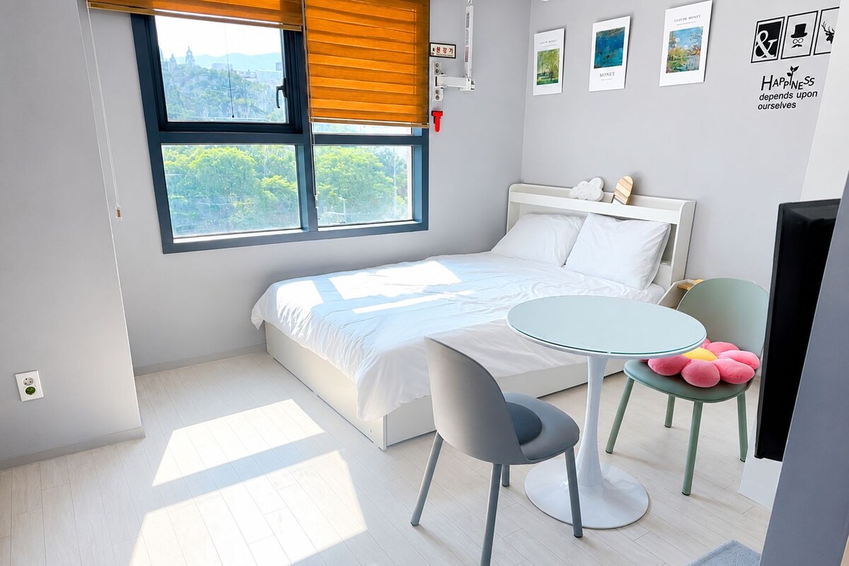 Un dormitorio con una cama, una mesita, una silla y una ventana con persianas.
