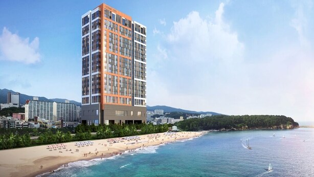 Un hotel de gran altura con varias plantas, una playa al fondo y un cielo despejado.