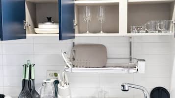 Una cocina con armarios blancos, un lavabo y diferentes utensilios.
