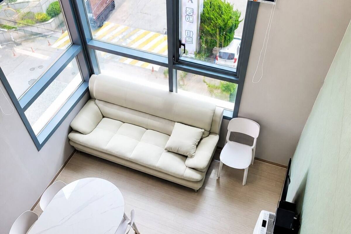 Ein stilvolles Zimmer mit einer weißen Couch, einem weißen Tisch und großen Fenstern.