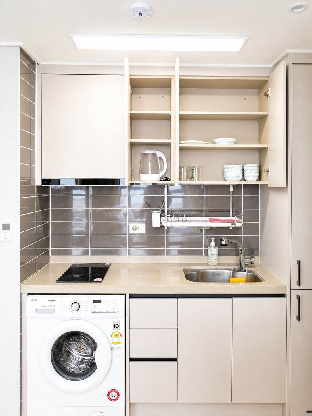 A compact kitchen with a built-in washer, a sink, and a coffee maker.