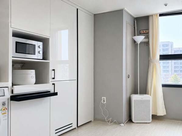Una cocina compacta con microondas, horno integrado y un refrigerador pequeño.