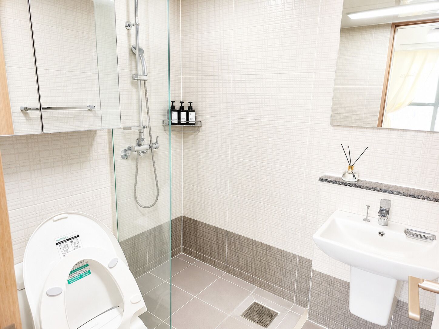 A modern bathroom with a glass shower enclosure, a white toilet, and a sink with a mirror above.
