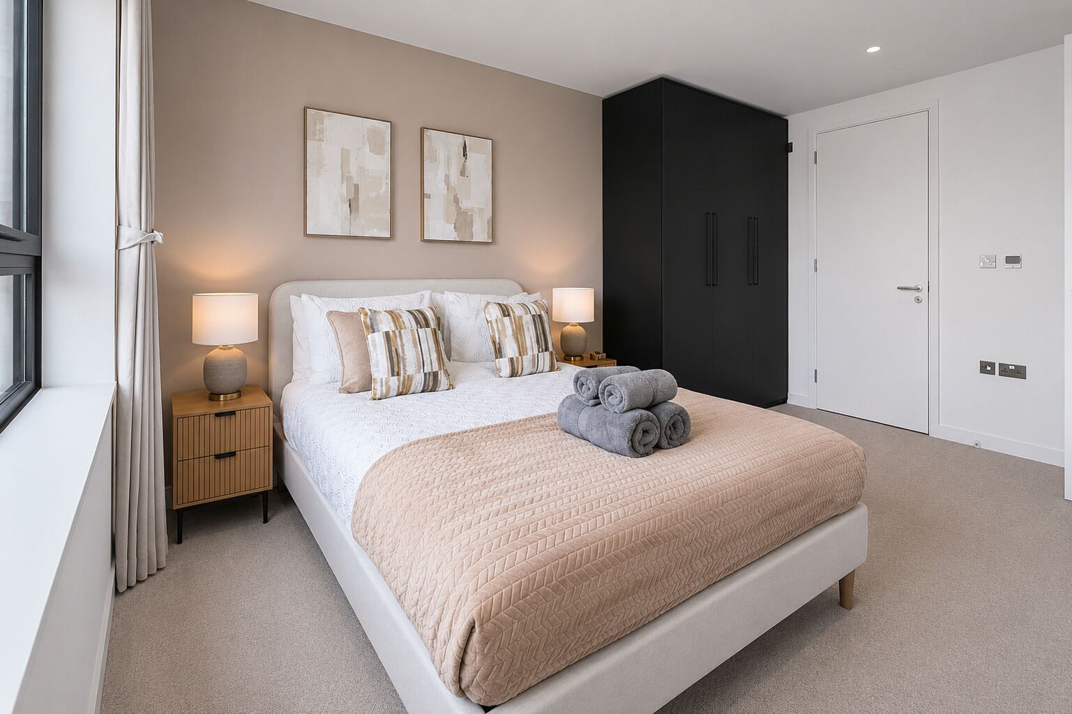 Ein modernes Schlafzimmer mit einem großen Bett, Nachttischlampen, einem Kleiderschrank und Bildern an der Wand.