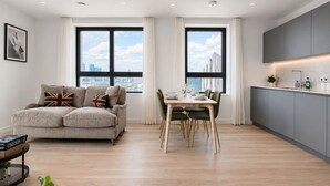 A modern living room with a sofa, dining table, and kitchen area. - Stylish Greenwich flat near The O2 with Balcony & Wi-Fi (London)