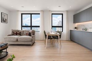 Ein modernes Wohnzimmer mit einer Couch, einem Esstisch und einer Küchenzeile.