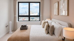 A hotel room with a large bed, a view of the city, and a cityscape through the window. - Stylish Greenwich flat near The O2 with Balcony & Wi-Fi (London)