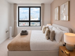 Ein Hotelzimmer mit einem großen Bett und Blick auf die Stadt, mit Stadtbild im Fenster.