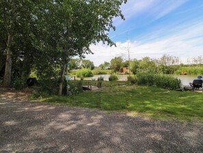 Ein Flussufer-Campingplatz mit Holzterrasse, kleiner Lagerhütte und Angelplatz.