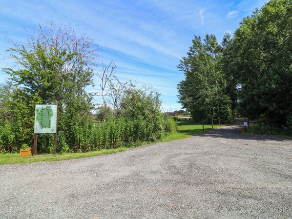 A gravel path leading to a building with a green informational sign.