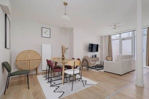 A modern living room with a dining area, a sofa, a TV, and large windows. - Spacious apartment 8PAX in the center (Paris)