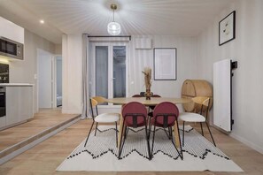 Eine moderne Küche mit Mikrowelle, ein Essbereich mit Tisch und Stühlen sowie ein großes Fenster mit Vorhängen.
