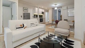 A modern living room with a sofa, coffee table, and dining area. - Spacious apartment 8PAX in the center (Paris)