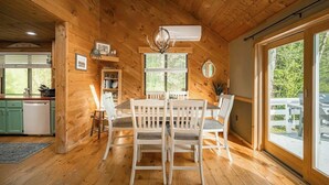 Een houten interieur met een eettafel, stoelen en een kroonluchter.