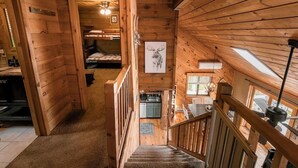 Een houten chalet van binnen met een trap, stapelbedden, een keukenhoek en een foto van een hert.