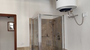 A shower enclosure with a glass door, a white cabinet, and a wall-mounted water heater.