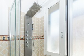 A shower with a glass enclosure, a control panel, and a tiled wall with a geometric pattern. - Amazing 12-bed apartment with 4 bedrooms in Rimini, 30 meters from the beach (Rimini)