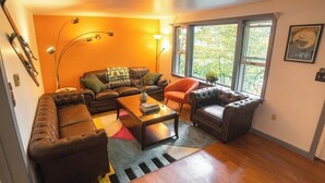 Ein Wohnzimmer mit Sofa, Sesseln, Couchtisch und einem großen Fenster.