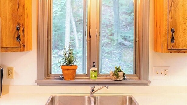 Eine Küche mit einem Oberlicht, Holzschränken, einem Spülbecken und einem Blumentopf.