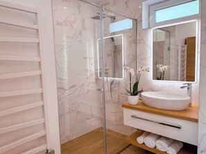 A modern bathroom with a glass-enclosed shower, a white sink, and a mirror above it. - Premium apartment in the center of Tihany, with an outdoor hot tub and infrared sauna. (Tihany)