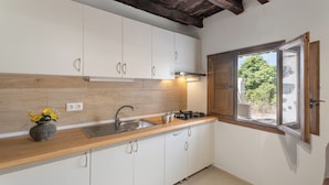A kitchen with white cabinets, a wooden countertop, a gas stove, a sink, and a window with wooden shutters. - Charming Farmhouse Retreat in Arona With Stunning Views (Arona)