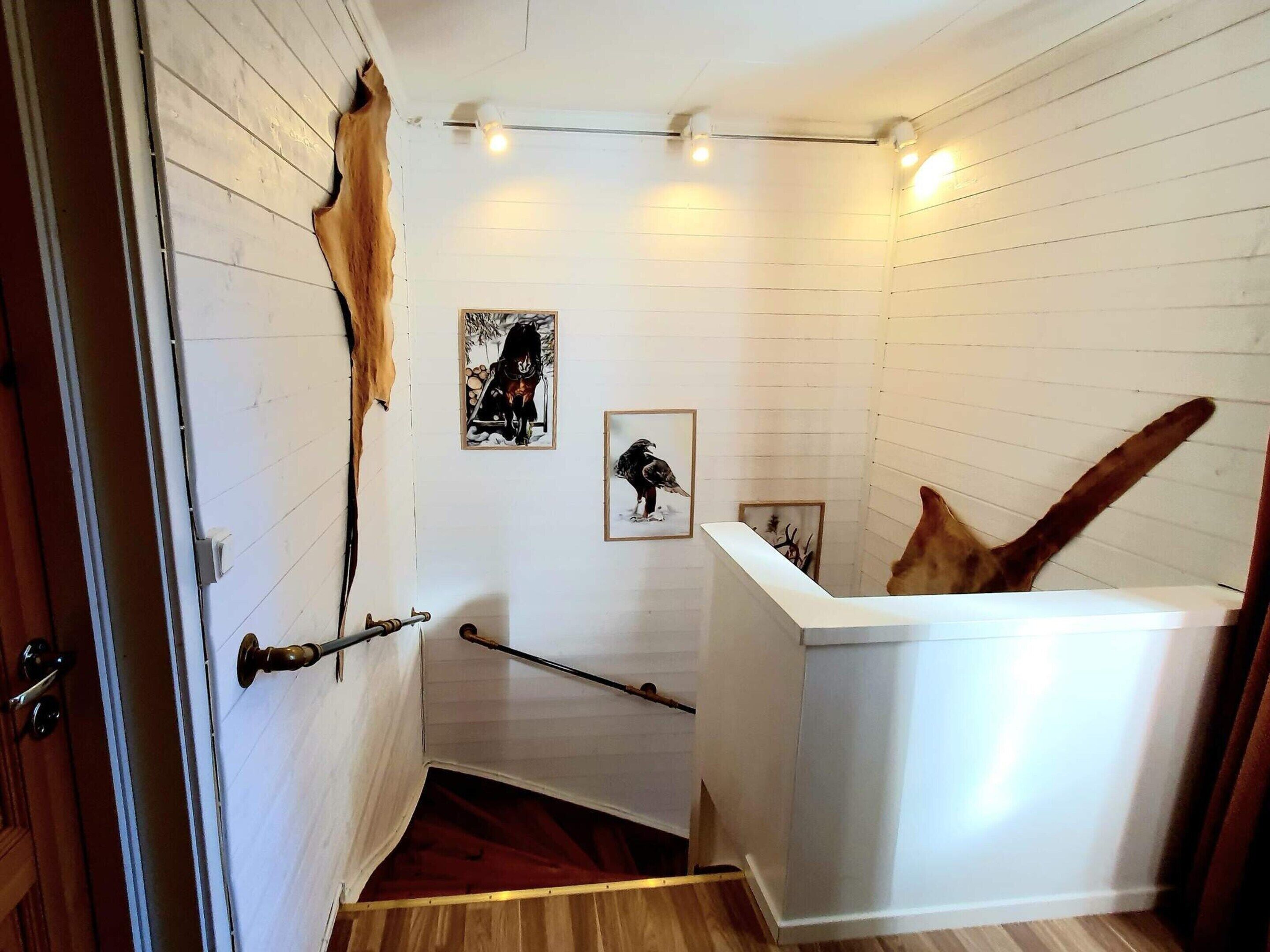 A room with white paneled walls, a wooden floor, a white reception desk, and a door with a brass handle.