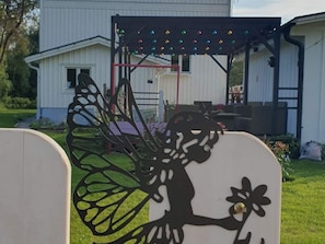 Un jardin avec une maison blanche, une clôture en métal et une sculpture décorative en métal.
